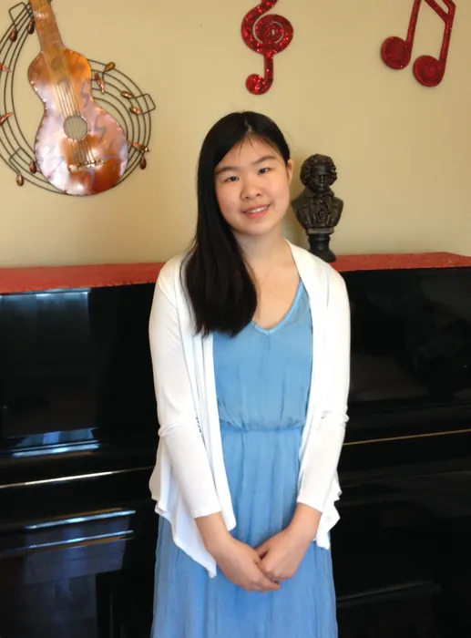 Amy standing by a piano